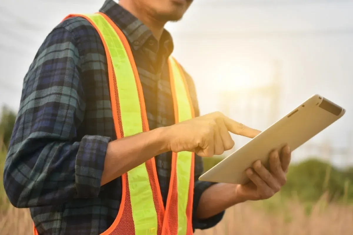 Field worker using tablet in hi-vis vest outdoors